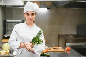 cooking and food concept. smiling female chef, cook or baker chopping vegetables photo