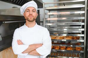 Happy baker standing near tray with bread at the bakery photo