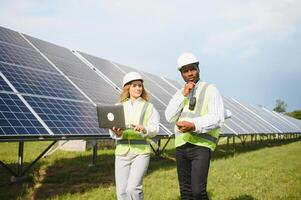 africano americano empresario y europeo hembra ingeniero hablando cerca solar paneles foto