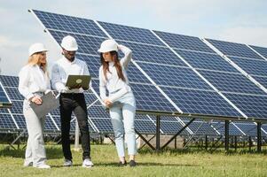 retrato de ingenieros en pie fuera de cerca solar paneles Tres trabajadores, dos mujer y uno hombres foto