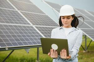 solar paneles y inversor con ordenador portátil. negocio mujer con ordenador portátil cerca solar paneles verde energía para hogar y negocio foto