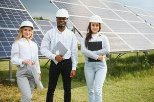 retrato de ingenieros en pie fuera de cerca solar paneles Tres trabajadores, dos mujer y uno hombres foto