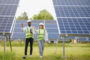 africano americano empresario y europeo hembra ingeniero hablando cerca solar paneles foto