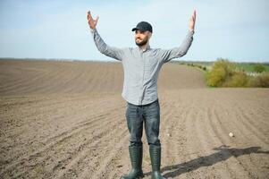 A farmer in boots works in a field sown in spring. An agronomist walks the earth, assessing a plowed field in autumn. Agriculture. photo