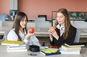 A cute girl smiling at her classmate while having lunch at the desk in school during a break photo