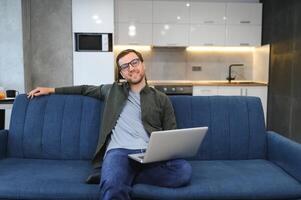 Side view handsome young businessman in eyewear working with computer. Pleasant happy man communicating in social network, searching information online photo