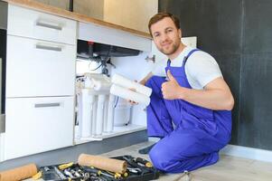 Plumber installs or change water filter. Replacement aqua filter. Repairman installing water filter cartridges in a kitchen. Installation of reverse osmosis water purification system. photo