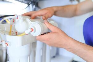 Plumber installs or change water filter. Replacement aqua filter. Repairman installing water filter cartridges in a kitchen. Installation of reverse osmosis water purification system. photo