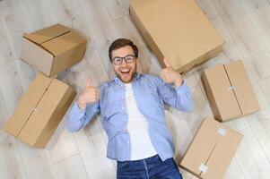 Young caucasian man at a new home with cardboard boxes photo