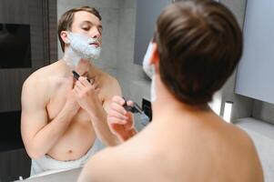 Confident guy using shaver in bathroom photo