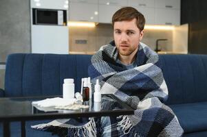 Sick man on sofa at home in living room. man feeling sick with cold and fever at home, ill with flu disease sitting on the sofa. It's the season of sneezes. photo