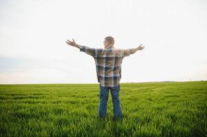 Portrait of senior farmer standing in wheat field examining crop during the day. photo