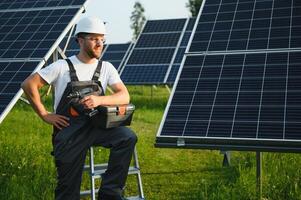 Side view of male worker installing solar modules and support structures of photovoltaic solar array. Electrician wearing safety helmet while working with solar panel. Concept of sun energy photo
