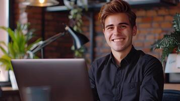 Cheerful Young IT Professional Smiling at Desk with Laptop in Cozy Office Setting photo