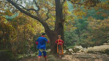 People in traditional attire posing under a tree in autumn forest video