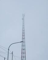 The tower base of the transceiver system towers high in the mountains with dense fog photo
