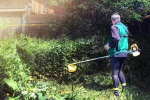 Man mows and cuts the grass with a gasoline trimmer in the garden. Mows tall grass. photo