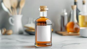 Glass bottle with cork lid containing amber liquid, placed on a marble countertop with blurred kitchen utensils in the background. photo