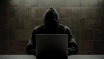 hacker with laptop computer on dark background photo