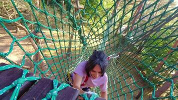 HBH adventure park, Palanga, Lithuania -2023 - woman use safety net in adventure park climb net up to platform. Exercise in the woods. Adventure parks extreme sports in Lithuania video