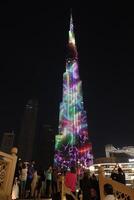 burj khalifa with towers and buildings in the night with small lake photo