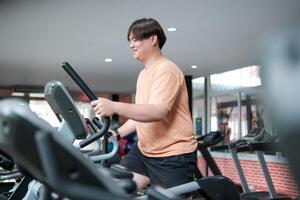 Overweight man smiling while exercising on elliptical photo