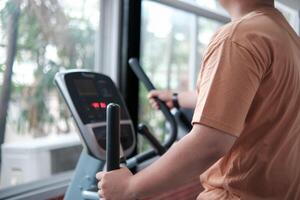 Overweight man exercising on an elliptical machine in the gym photo