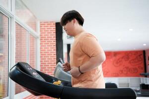 Overweight man running on treadmill in gym photo