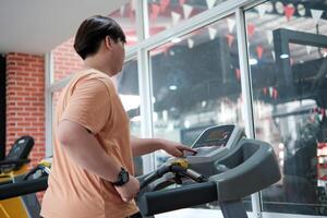 Overweight man running on treadmill in gym photo
