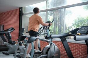 Overweight man exercising on an elliptical machine in the gym photo