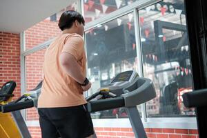 Overweight man running on treadmill in gym photo