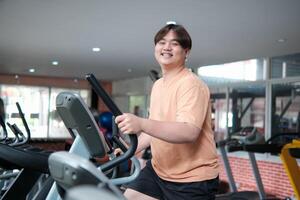 Overweight man smiling while exercising on elliptical photo
