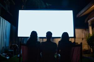 Three people are sitting in lawn chairs in front of a large screen photo
