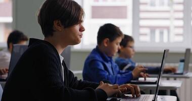 alunos dentro baseado em computador Sala de aula do Alto escola, adolescentes estudantes trabalhando com laptops video