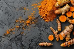 Turmeric roots and powder on dark textured background photo