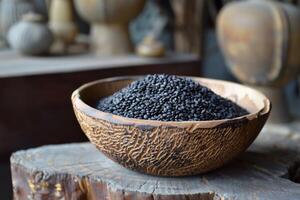 Rustic wooden bowl overflowing with black sesame seeds on a tree trunk photo