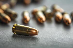 9mm bullet laying on a table with more bullets in the background out of focus photo