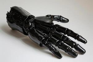 Black artificial hand prosthesis is lying on white surface photo