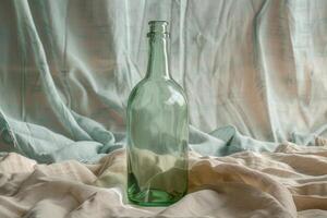 Empty green glass bottle standing on a draped cloth photo