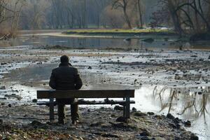 Man sitting on bench contemplating low water levels in nature photo