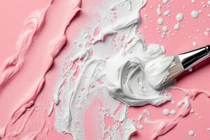 Artistic paintbrush with white paint on pink background photo