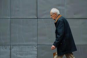 Elderly man walking by a modern wall photo