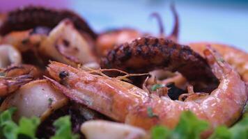 Chef arranging with a tongue nicely grilled shrimp prawns on a serving plate with greens on top in 4K. King shrimps being served video