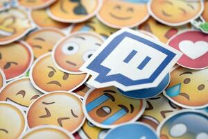 KYIV, UKRAINE - APRIL 20, 2024 Twitch logo and large set of stickers with Emoji yellow faces. Emoji is a pictogram or smiley embedded in text and used in electronic messages photo
