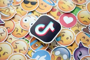 KYIV, UKRAINE - APRIL 20, 2024 TikTok logo and large set of stickers with Emoji yellow faces. Emoji is a pictogram or smiley embedded in text and used in electronic messages photo