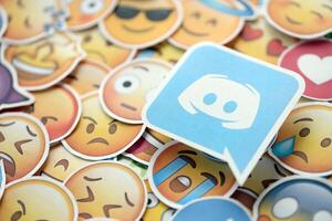 KYIV, UKRAINE - APRIL 20, 2024 Discord logo and large set of stickers with Emoji yellow faces. Emoji is a pictogram or smiley embedded in text and used in electronic messages photo
