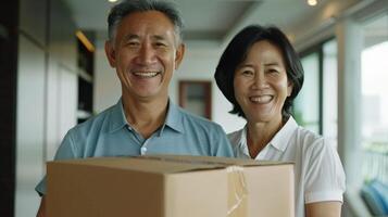 Smiling senior couple holding a cardboard box, standing in a modern living room, ready for moving or receiving a package. photo