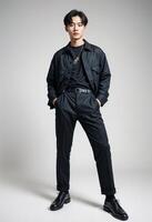 Young Korean Man in Black Outfit. poses confidently against a neutral background. photo