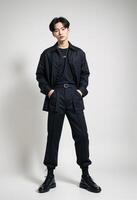 Young Korean Man in Black Outfit. poses confidently against a neutral background. photo
