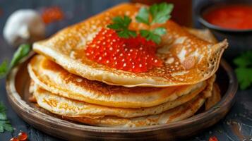 Russian pancakes with red caviar. Stack of pancakes topped with red caviar and parsley on a plate photo